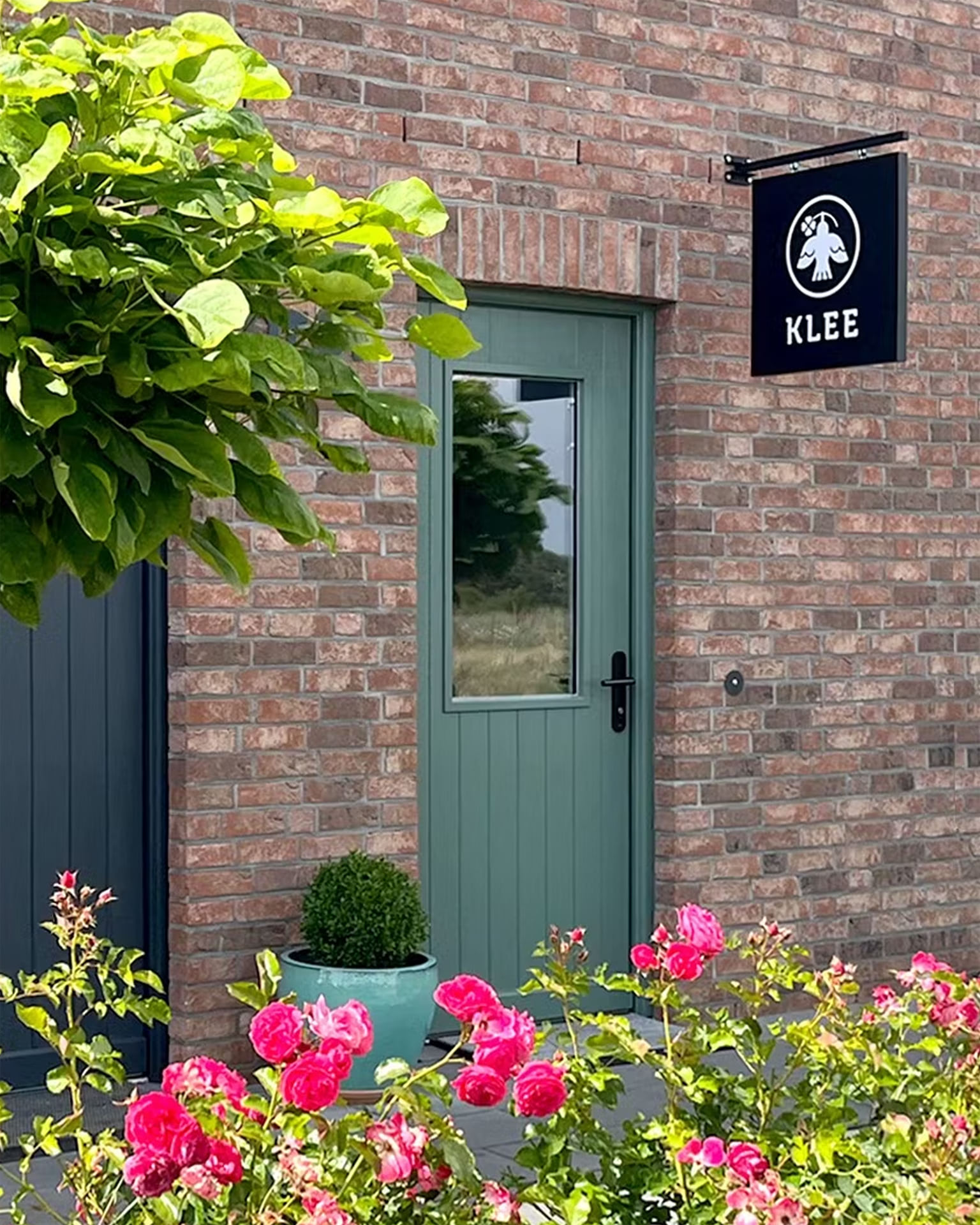 KLEE Eingang mit Logo-Fahne an der Backsteinfassade